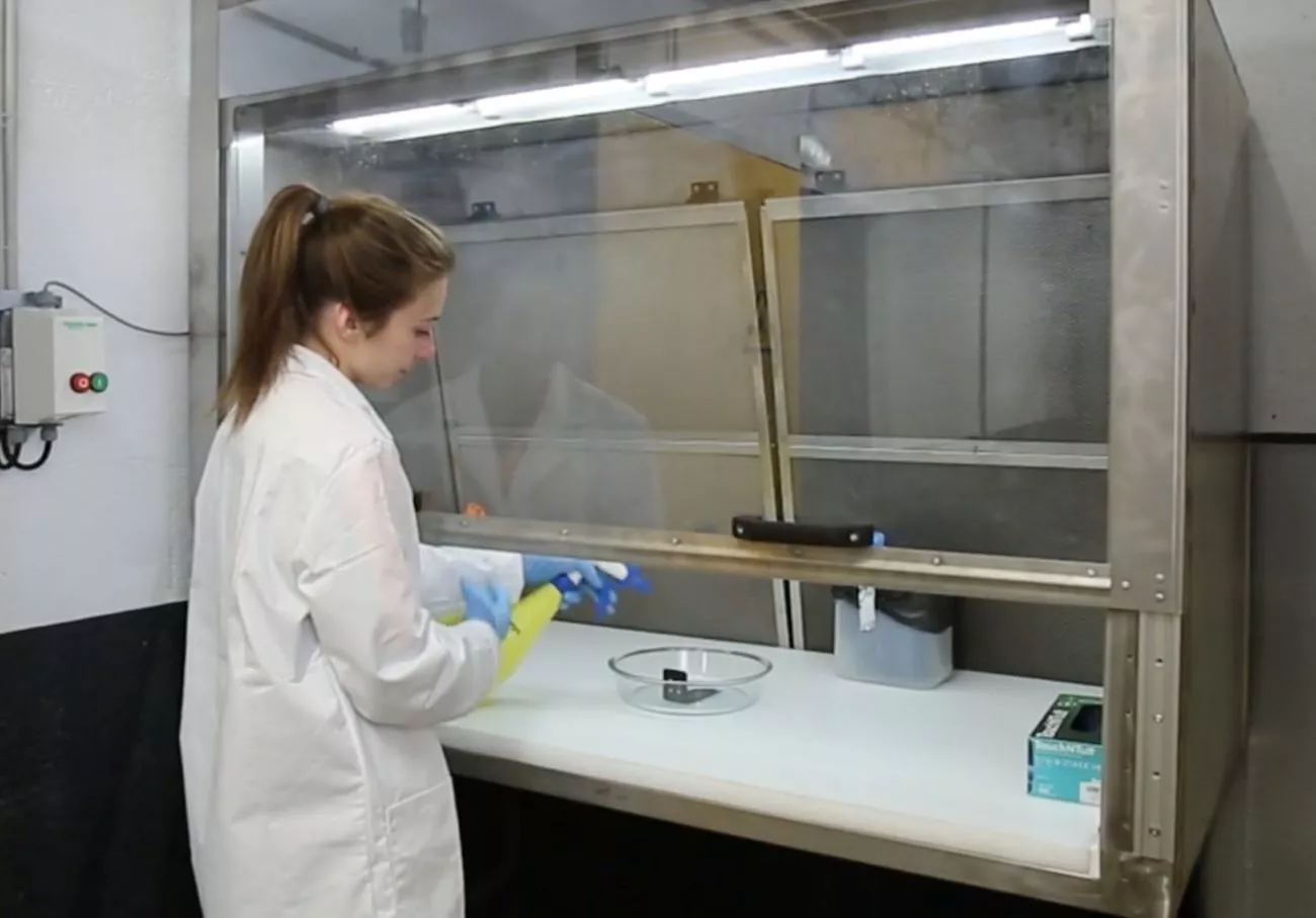 Operator in front of a fume cupboard to initiate fluid resistance tests
